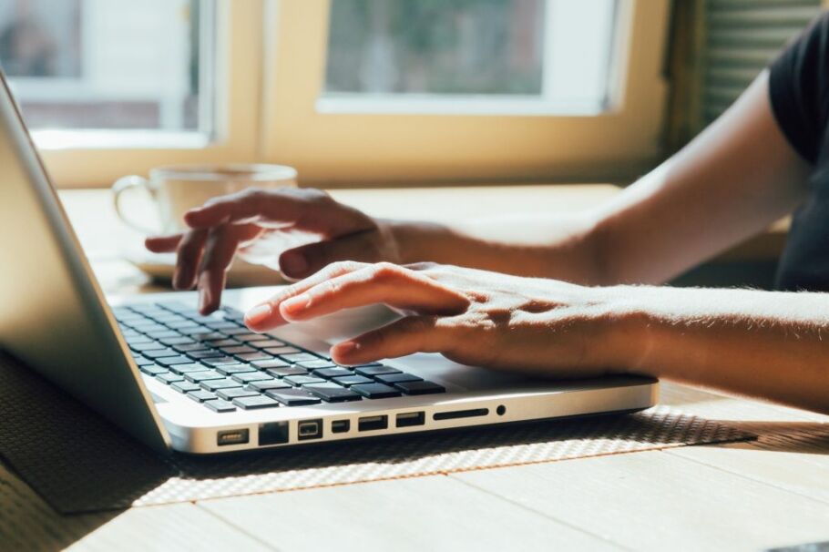Student types on laptop, preparing college applications with IvyWise support.