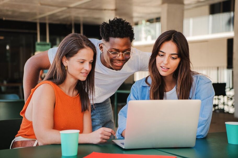 Students collaborate on a laptop, possibly researching college admissions information.