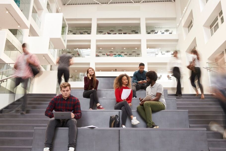 Diverse students collaborate and study in a modern college building.