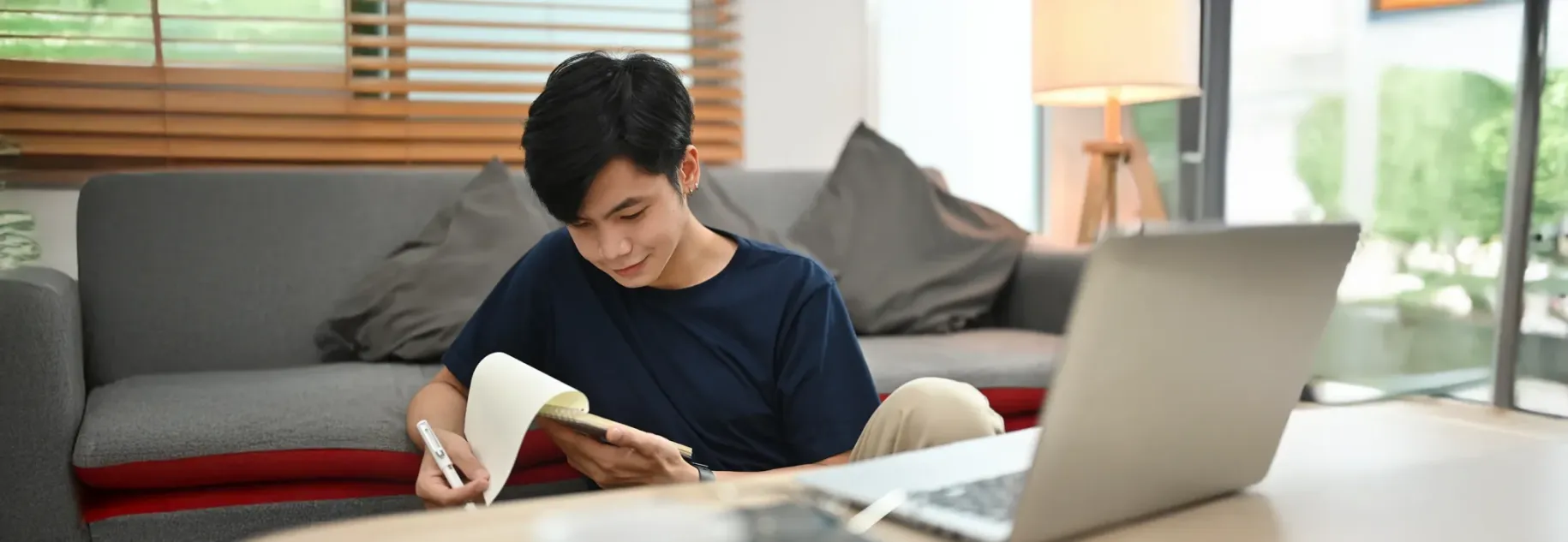 Student studying at home with laptop and notebook for college applications.