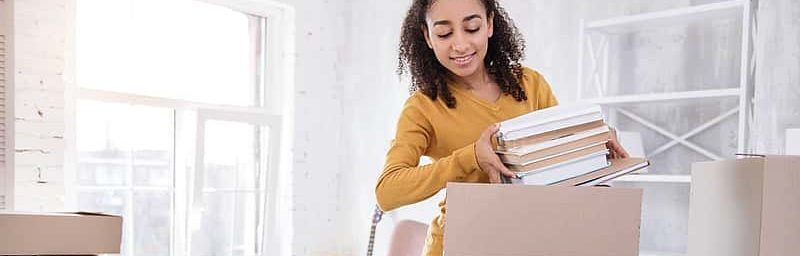 Student packing books into a box, preparing for college.
