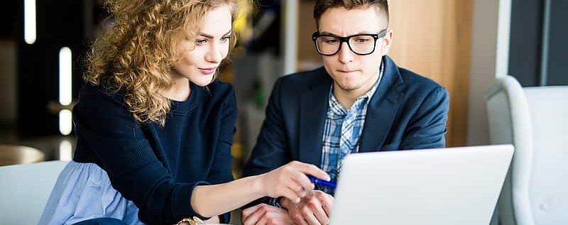 Counselor advises student on college applications using a laptop computer.