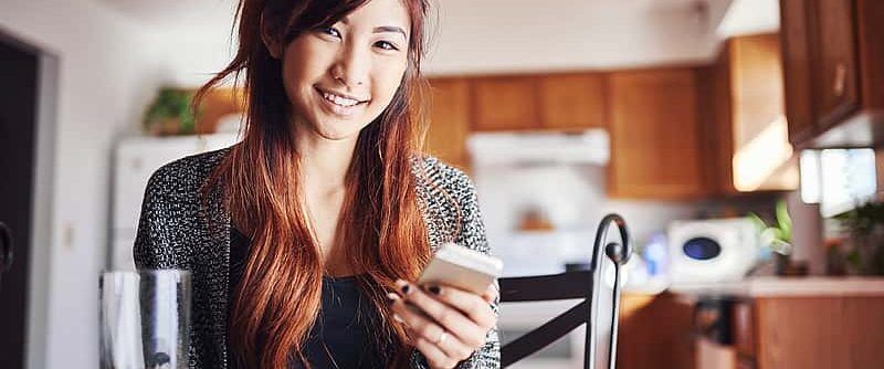 Smiling student using phone, possibly researching college admissions information.