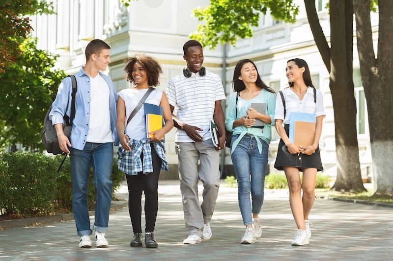 Five students walking together on a college campus