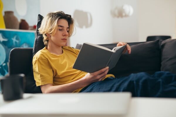 teen boy reading book at home
