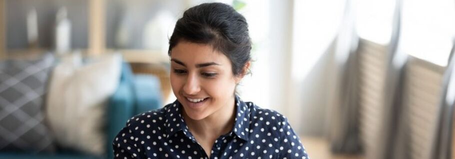 Smiling student in polka dot shirt focused on her college application.