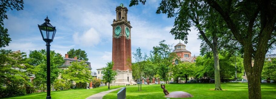 College campus with clock tower, green lawn, and academic buildings.