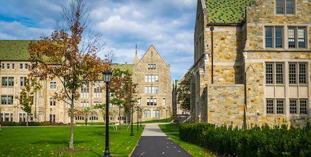 College campus buildings with green roofs and stone walls on a sunny day.
