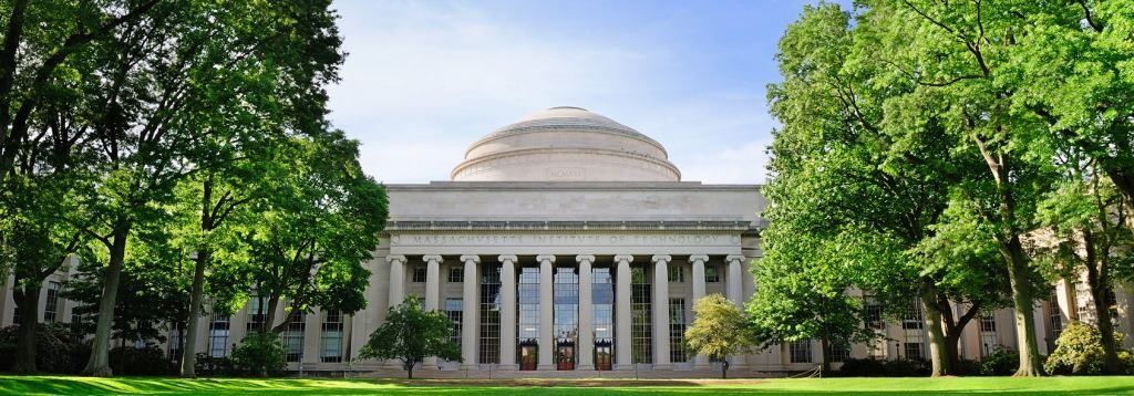 MIT's iconic Great Dome framed by trees on a sunny day.