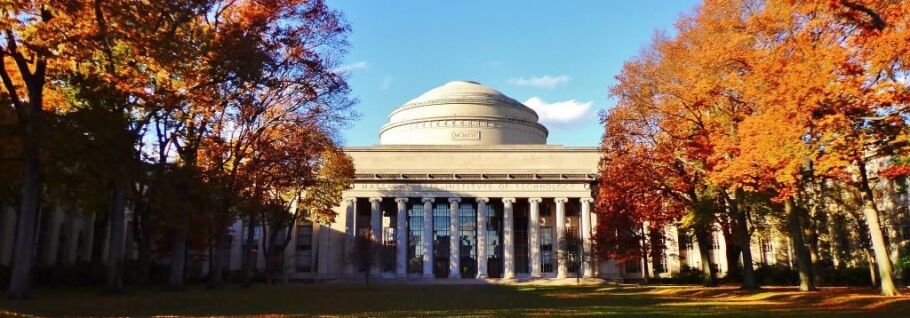 MIT's iconic Great Dome framed by autumn foliage on a sunny day.