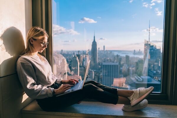 Female student typing on laptop overlooking New York City skyline