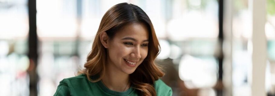 Smiling student looks down, perhaps at college application or test prep materials.