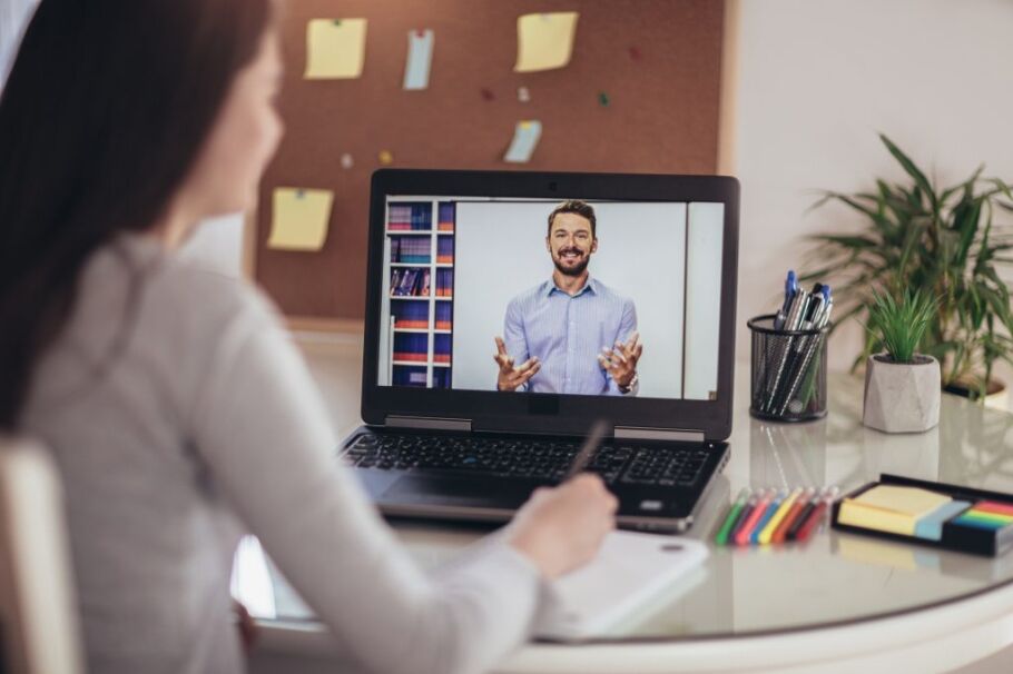 Student attends online college counseling session and takes notes.