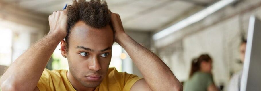 Stressed student with hands on head, overwhelmed by college application process.