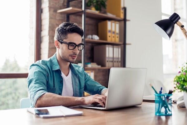 Male grad student working on laptop at a desk