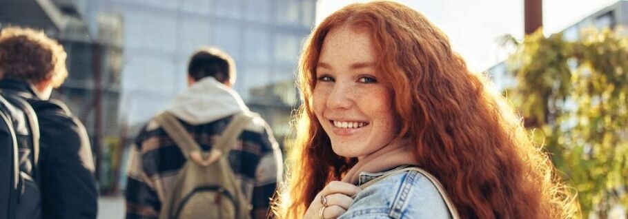 Smiling student with backpack on campus, ready for college success.