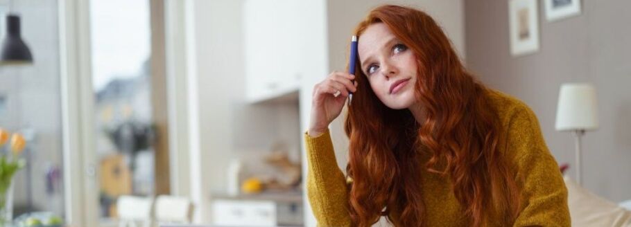 Student thoughtfully considers college essay topics with pen in hand.