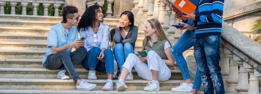 Diverse students sitting on steps, talking and studying together.