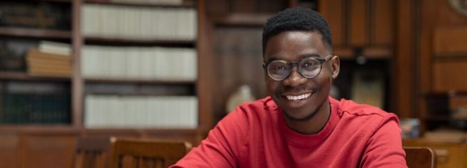 Smiling student in library setting, representing academic success and college preparation.