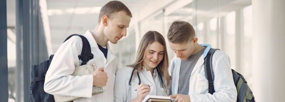 Pre-med students collaborate on notes in a bright, modern hallway.