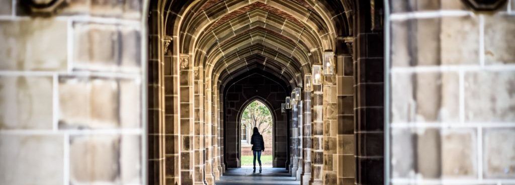 Student walking through a stone archway, symbolizing the path to college.
