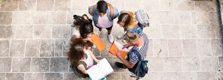 College students collaborate on schoolwork outdoors, seen from above.