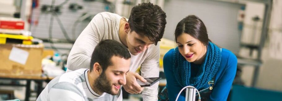 Students collaborate on a project, possibly engineering, using a tablet.