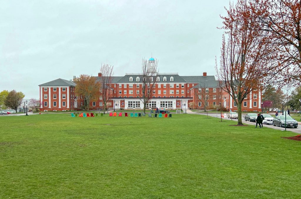 College campus lawn with colorful chairs and brick academic building.