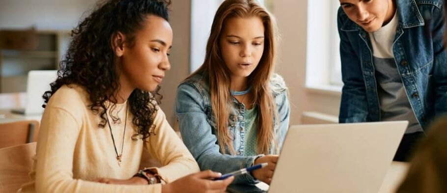 Students collaborate on a laptop, working together on a school project.