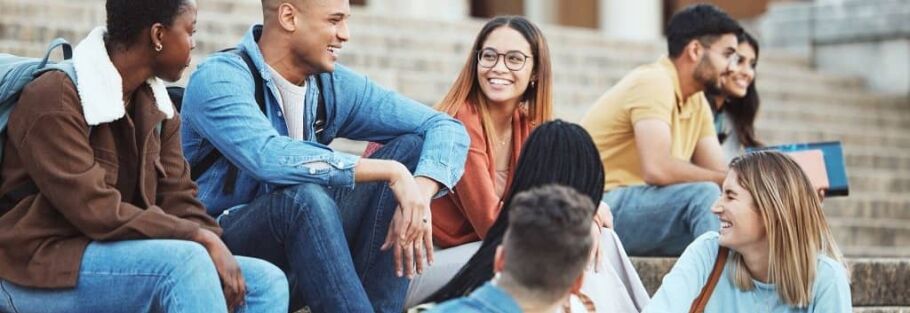 Smiling college students sitting on steps, possibly discussing academics or campus life.