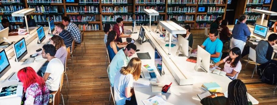 Students studying and working on computers in a university library.