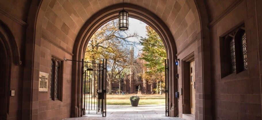 View of a college campus through an arched stone gateway.