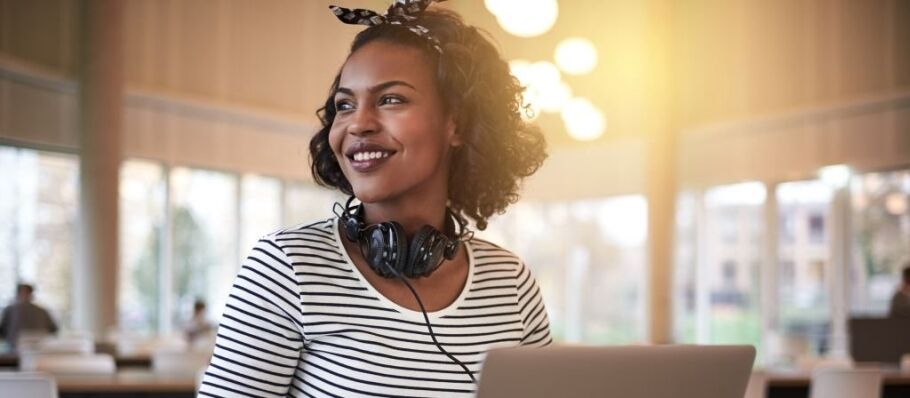 Smiling student with laptop and headphones looks toward her bright future.