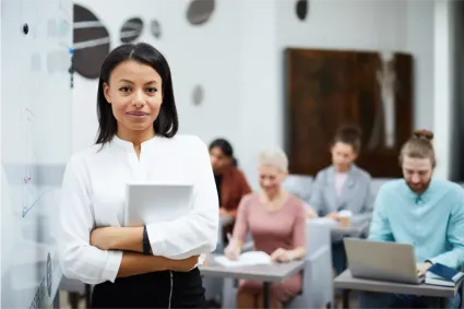 Educator in a classroom with diverse students, holding a tablet