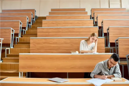 Students taking notes in a lecture hall, focused on academic success.