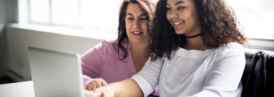 Mother and daughter review college applications together on a laptop.
