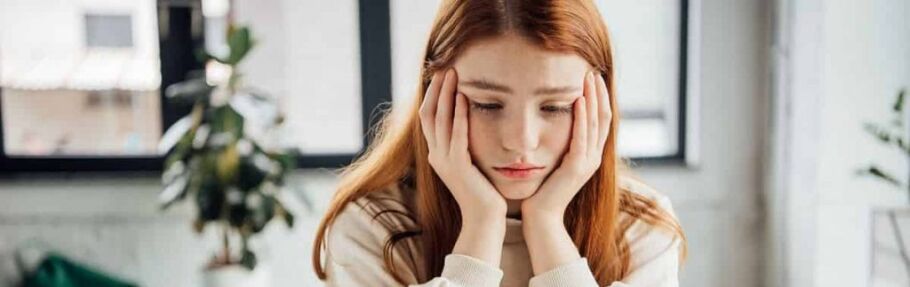Student holding head in hands displaying visible distress over deferred application status
