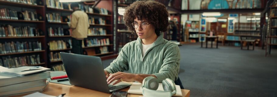 Student studying with laptop, focused on academic success and college preparation.