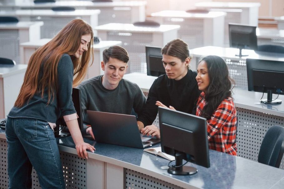 Students collaborate on a laptop in a modern study space.