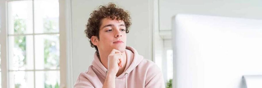 Teen student thoughtfully considers college options on computer.