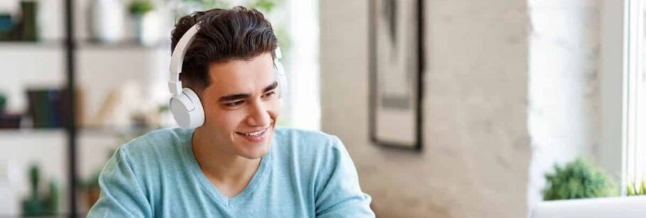 Student wearing headphones smiles while studying or attending online class.