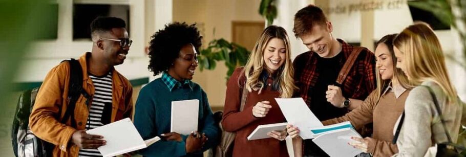 Smiling college students look at papers, representing academic success and collaboration.
