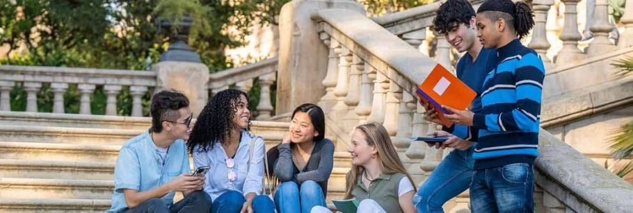 Diverse students studying together on stone steps, possibly on a college campus.