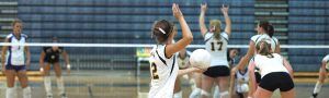 High school volleyball team playing a game, showcasing teamwork and athletic skills.