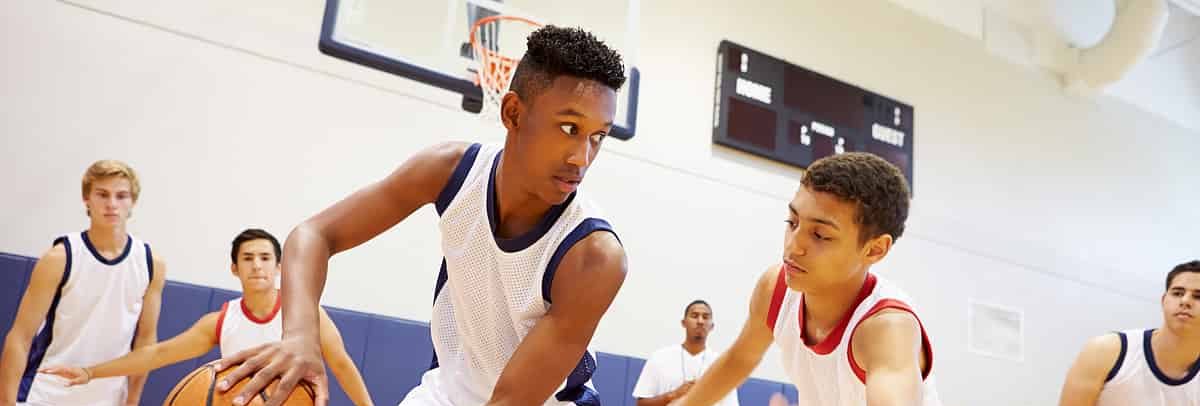 Student athletes playing basketball, demonstrating teamwork and dedication.