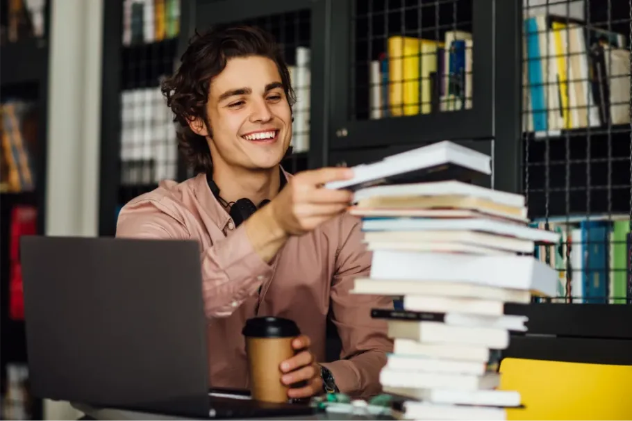 Smiling student with laptop, coffee, and books ready for college success.
