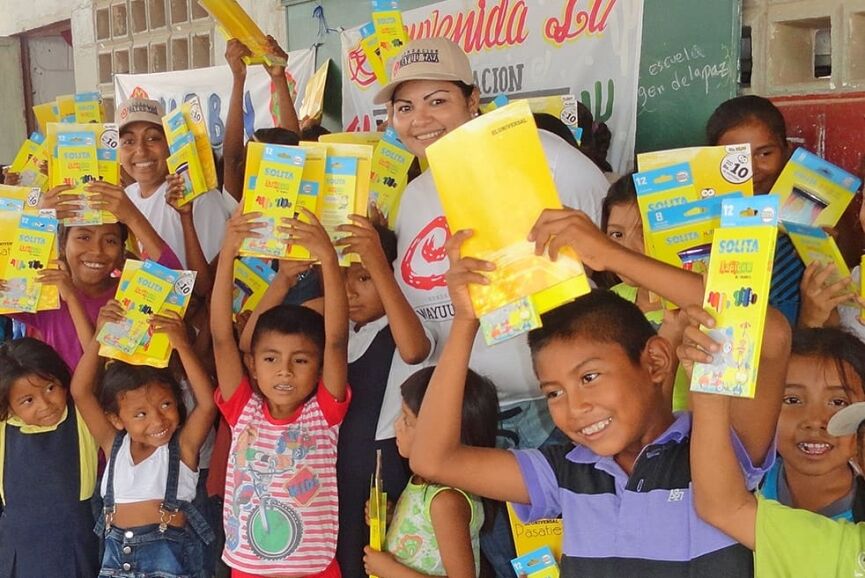 Children smiling, holding school supplies, symbolizing access to education and brighter futures.