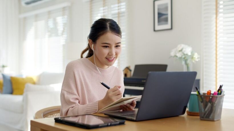Student learning online, taking notes during a virtual college counseling session.