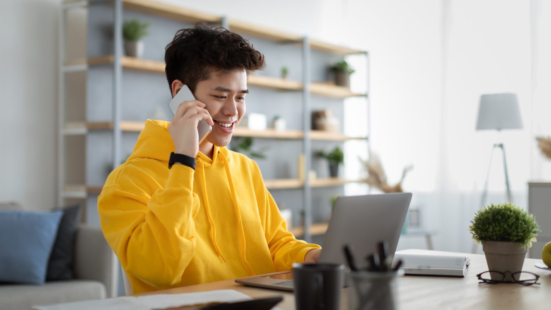 Student on phone with laptop, possibly discussing college applications.