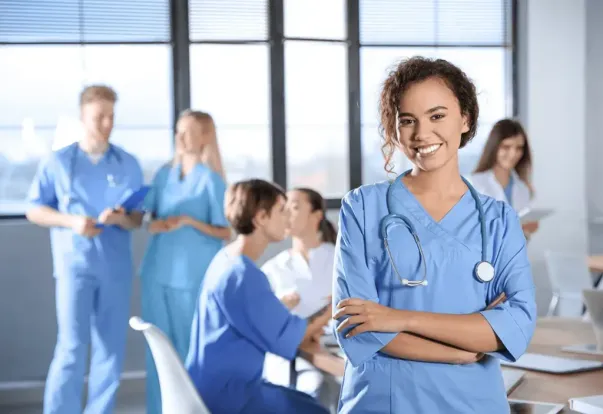 Smiling student in scrubs with stethoscope, considering a medical career path.